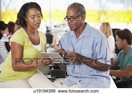 Stock Photo - Workers Using Digital Tablet In Busy Creative Office. Fotosearch