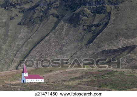 Stock Image - Church at Vik dwarfed by mountains, Iceland. Fotosearch