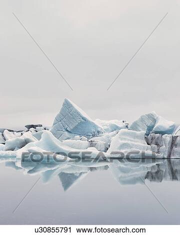 Stock Image - Striped icebergs at Jokulsarlon lagoon, misty sunrise, Iceland. Fotosearch