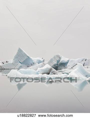 Stock Photo - Striped icebergs at Jokulsarlon lagoon, misty sunrise, Iceland. Fotosearch