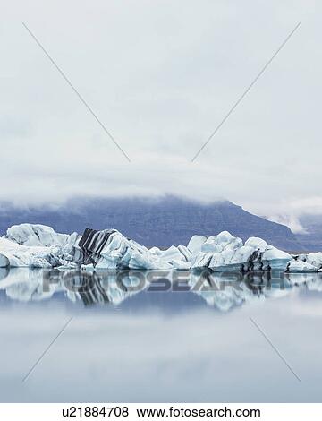 Stock Photo - Striped icebergs at Jokulsarlon lagoon, misty sunrise, Iceland. Fotosearch