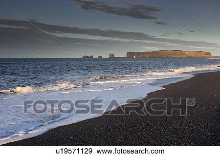 Stock Photo - Sunrise over Dyrholaey rock arch formation, Iceland. Fotosearch