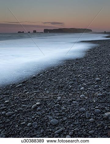 Stock Photo - Sunrise over Dyrholaey rock arch formation, Iceland. Fotosearch