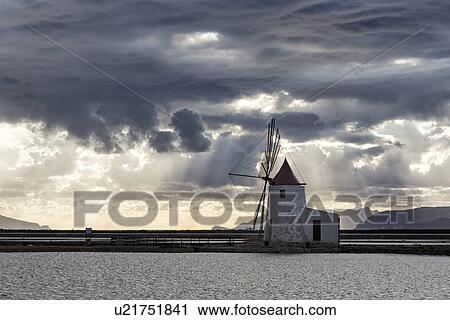 Stock Image - Windmills at Trapani saline pans, sunset, Sicily, Italy. Fotosearch