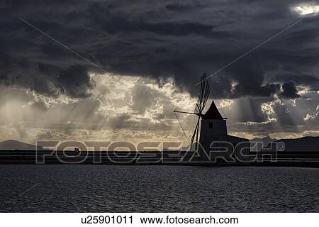 Stock Image - Windmills at Trapani saline pans, sunset, Sicily, Italy. Fotosearch