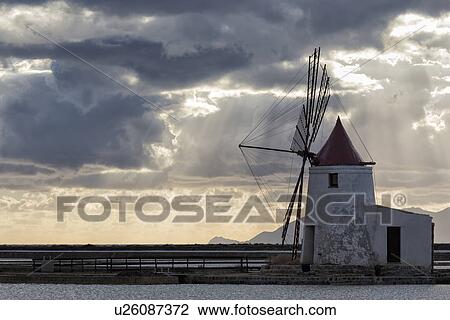 Stock Image - Windmills at Trapani saline pans, sunset, Sicily, Italy. Fotosearch