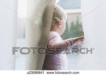 Baby girl (12-17 months) looking through window View Large Photo Image Stock Image - Baby girl (12-17 months) looking through window. Fotosearch