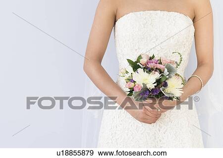 Bride in veil holding bouquet View Large Photo Image Stock Photo - Bride in veil holding bouquet. Fotosearch