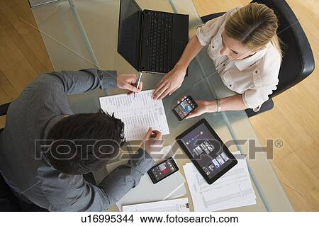 Picture - Business man and woman using mobile devices. Fotosearch