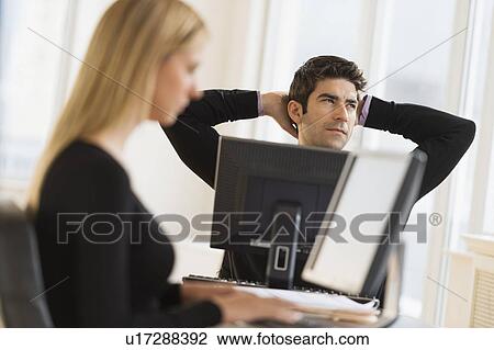 Stock Image - Business man and woman working in office. Fotosearch