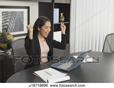Businesswoman expressing happiness at desk View Large Photo Image Stock Photograph - Businesswoman expressing happiness at desk. Fotosearch