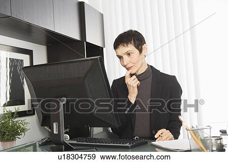 Stock Photo - Businesswoman working at desk. Fotosearch