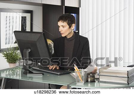 Stock Photograph - Businesswoman working at desk. Fotosearch