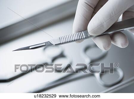 Close up of hand in surgical glove holding dental scalpel, studio shot View Large Photo Image Stock Photo - Close up of hand in surgical glove holding dental scalpel, studio shot. Fotosearch
