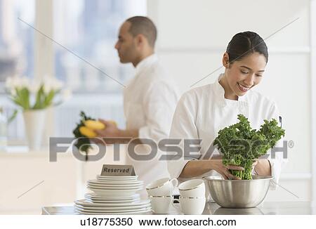 Stock Image - Couple during preparations in kitchen of their own restaurant. Fotosearch