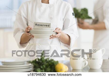 Stock Image - Couple during preparations in kitchen of their own restaurant. Fotosearch