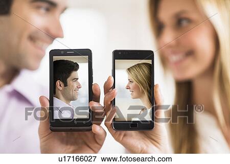 Stock Photo - Couple holding smartphones with their pictures on. Fotosearch