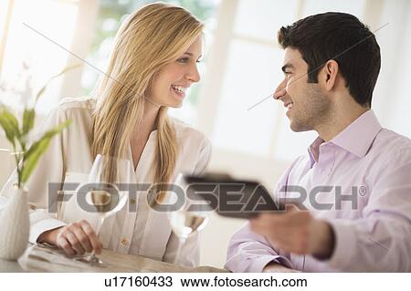 Stock Image - Couple in restaurant, man paying. Fotosearch