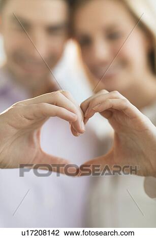 Stock Image - Couple making heart shape with hands. Fotosearch