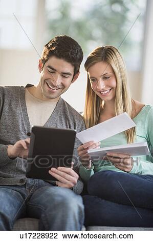 Stock Image - Couple using tablet pc to pay bills online. Fotosearch