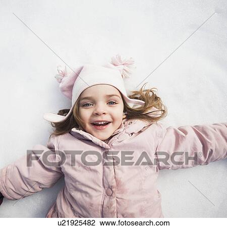 Stock Image - Directly above portrait of girl (2-3) lying on snow. Fotosearch