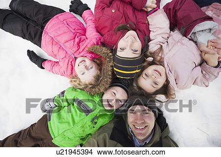 Directly above portrait of three children (2-3, 4-5) with parents lying on snow View Large Photo Image Picture - Directly above portrait of three children (2-3, 4-5) with parents lying on snow. Fotosearch
