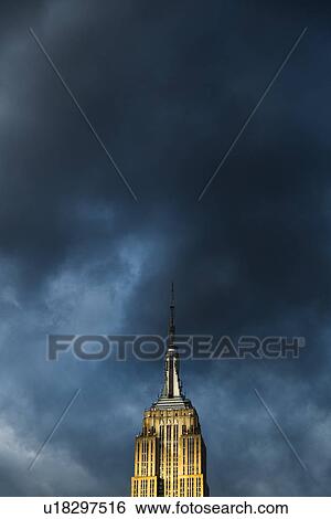 Empire State Building against cloudy sky View Large Photo Image Stock Photograph - Empire State Building against cloudy sky. Fotosearch