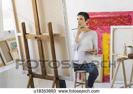 Stock Image - Female artist painting in her studio. Fotosearch