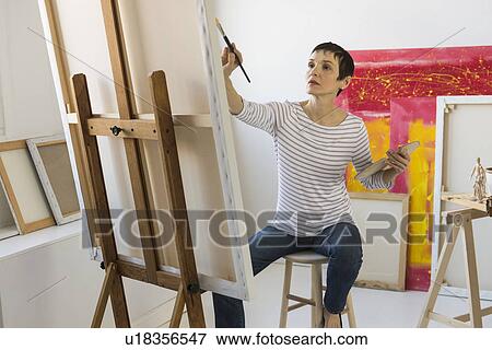 Stock Photo - Female artist painting in her studio. Fotosearch
