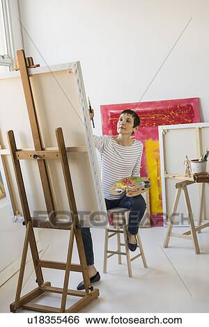 Stock Photograph - Female artist painting in her studio. Fotosearch