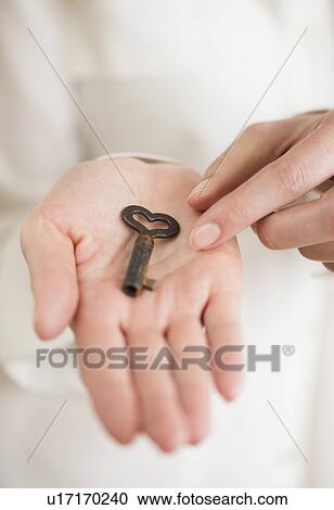 Stock Image - Female hand holding heart-shaped key. Fotosearch