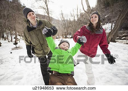 Stock Image - Front view of boy (4-5) with parents during stroll. Fotosearch
