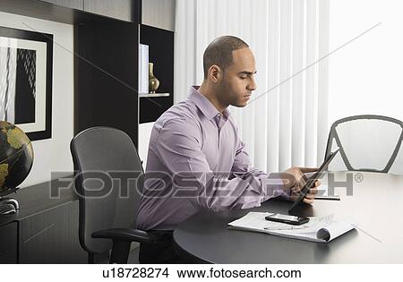 Male executive working at desk in office View Large Photo Image Picture - Male executive working at desk in office. Fotosearch