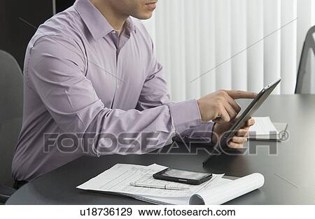 Male executive working at desk in office View Large Photo Image Stock Photo - Male executive working at desk in office. Fotosearch