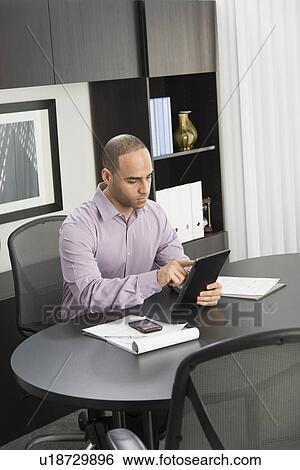 Male executive working at desk in office View Large Photo Image Stock Photograph - Male executive working at desk in office. Fotosearch