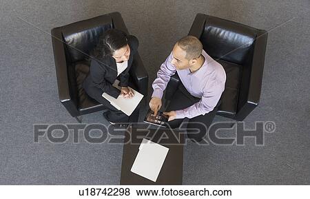 Stock Photo - Man and woman at meeting in office seen from above. Fotosearch