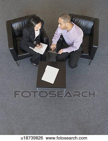 Stock Photograph - Man and woman at meeting in office seen from above. Fotosearch