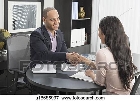 Stock Photo - Man and woman shaking hands in office. Fotosearch