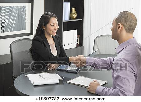 Stock Photo - Man and woman shaking hands in office. Fotosearch