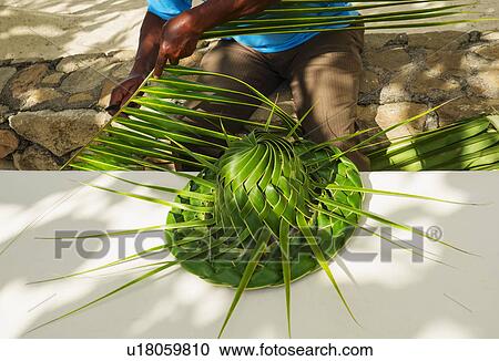 Stock Image - Man making hut with palm leaves. Fotosearch