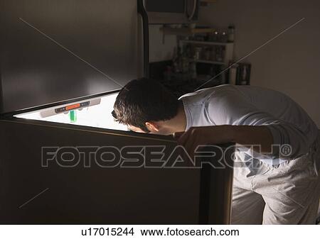 Picture - Man opening fridge at night. Fotosearch