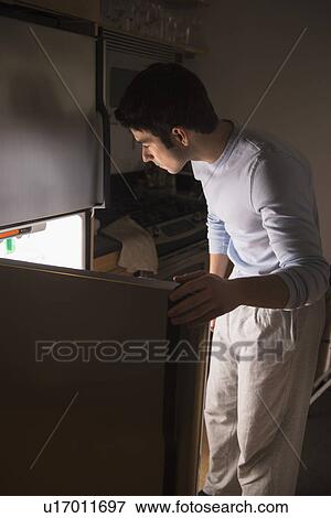 Stock Photo - Man opening fridge at night. Fotosearch