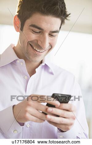 Picture - Man texting on smartphone. Fotosearch