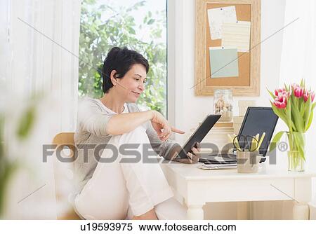 Mature woman using digital tablet and laptop View Large Photo Image Stock Photography - Mature woman using digital tablet and laptop. Fotosearch