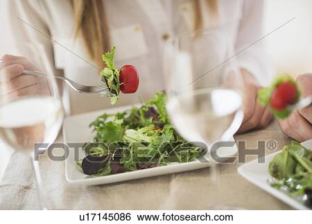 Stock Photograph - Midsection of woman eating salad. Fotosearch