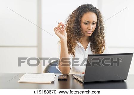 Office worker sitting by desk with laptop View Large Photo Image Stock Image - Office worker sitting by desk with laptop. Fotosearch