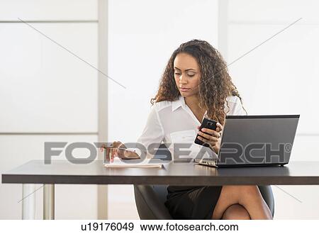 Office worker sitting by desk with laptop View Large Photo Image Stock Photo - Office worker sitting by desk with laptop. Fotosearch
