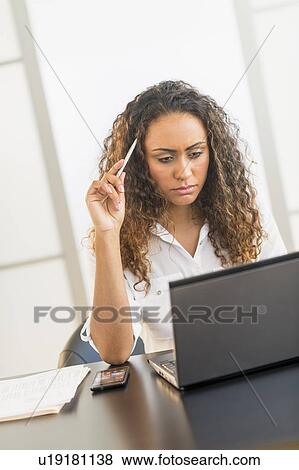Office worker sitting by desk with laptop View Large Photo Image Stock Photo - Office worker sitting by desk with laptop. Fotosearch