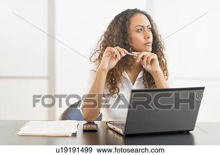 Office worker sitting by desk with laptop View Large Photo Image Stock Photo - Office worker sitting by desk with laptop. Fotosearch