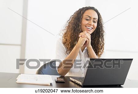 Office worker sitting by desk with laptop View Large Photo Image Stock Photo - Office worker sitting by desk with laptop. Fotosearch
